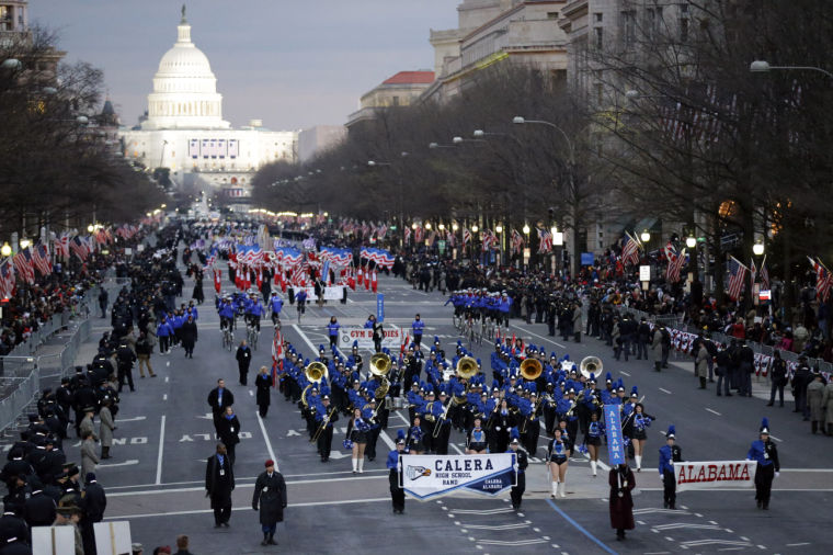 Parade with marching band in front, Gym Dandies behind them and a color guard in the back.